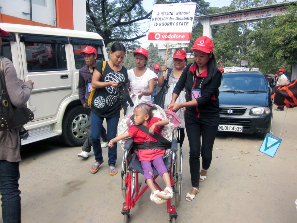 A volunteer assisting a differently abled child at the rally held on International Day of Persons with Disabilities, December 3, 2011. More than 200 persons with disability marched from Christian Higher Secondary School to Dimapur Town Hall. Volunteers from different NGOs and churches along with parents and guardians assisted them throughout the rally.  (Morung File Photo)